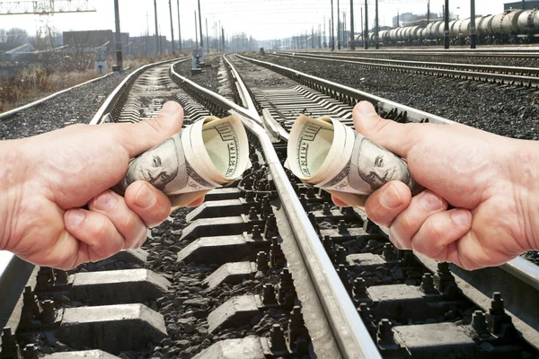 Mãos com notas de dólares contra a via férrea — Fotografia de Stock