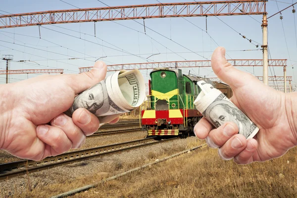 Hands with notes of dollars against the train on the railroad — Stock Photo, Image