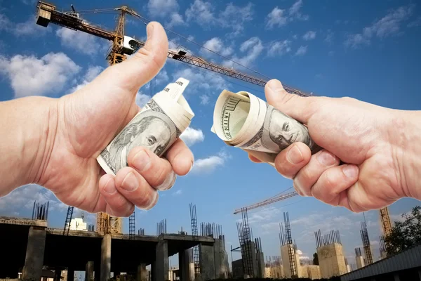 Hundred dollar notes of the USA in a hand against a construction Royalty Free Stock Images