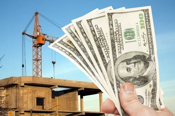 Hundred dollar notes of the USA in a hand against a construction Royalty Free Stock Photos