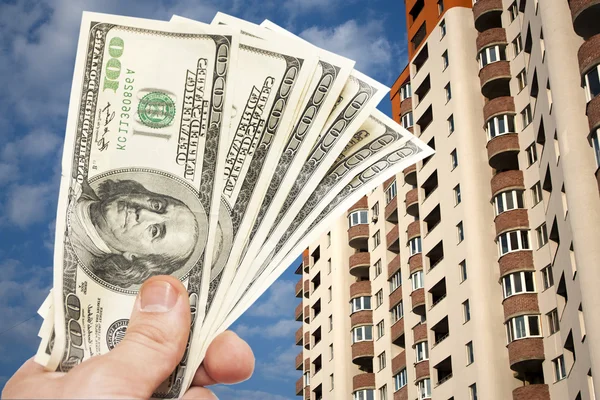 Долларовые купюры США в руке против обитаемого дома на высоком этаже — стоковое фото