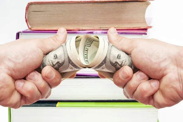 Dollar in een hand tegen met boeken — Stockfoto