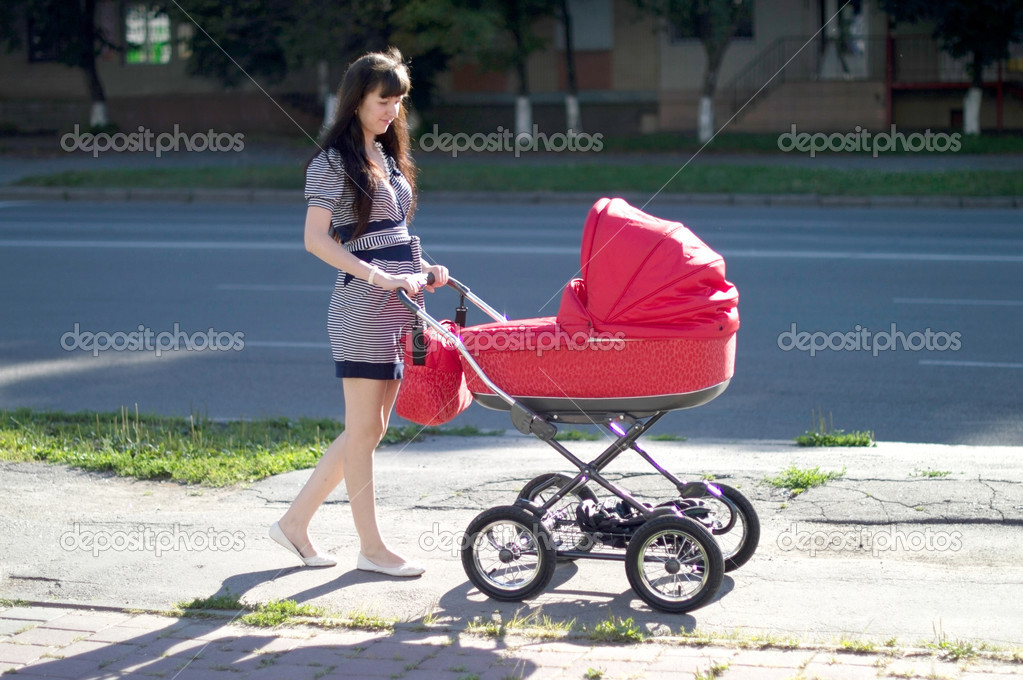 Young mother with a children's carriage on walk 