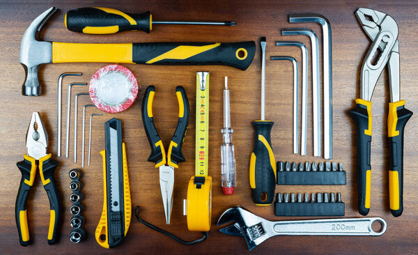 Different tools for working at home are set in Knoling style on the background of brown wooden boards