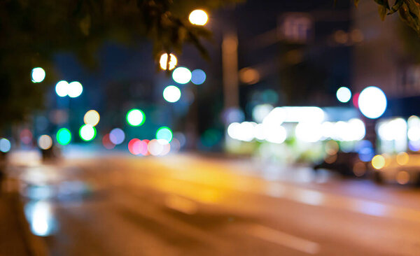 Blurred background of city street with cars and different lighting at night