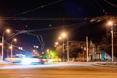 Şehirdeki asfalt yolda ilerleyen arabaların farlarından gelen bulanık ışık.