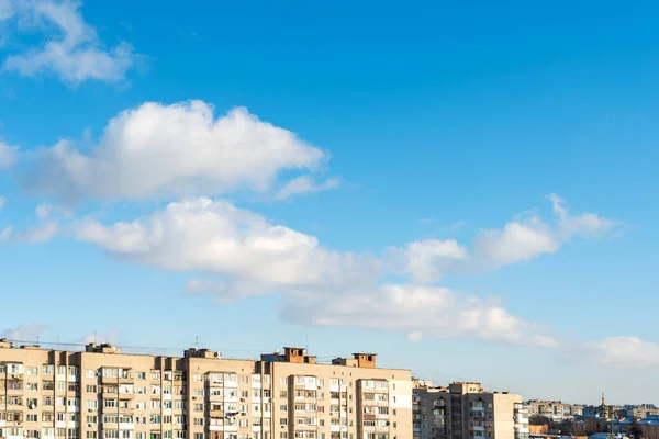 Městské Domy Pozadí Bílých Nadýchaných Mraků Modré Oblohy — Stock fotografie