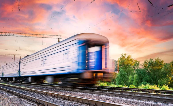 在日落的背景和美丽的天空下 蓝色的火车乘用车在快速的运动中模糊了方向 — 图库照片