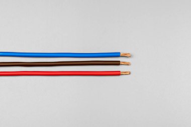 Kırmızı, mavi ve kahverengi izolasyonlu üç bakır kablo mat gri arka planda