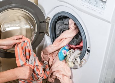 Çamaşır makinesinin yıkadığı renkli giysileri boşaltma işlemi.
