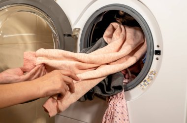 Çamaşır makinesinin yıkadığı renkli giysileri boşaltma işlemi.