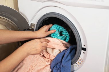 Çamaşır makinesinin yıkadığı renkli giysileri boşaltma işlemi.