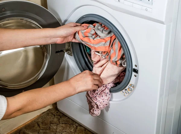 Çamaşır makinesinin yıkadığı renkli giysileri boşaltma işlemi.