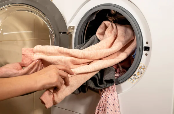 Çamaşır makinesinin yıkadığı renkli giysileri boşaltma işlemi.