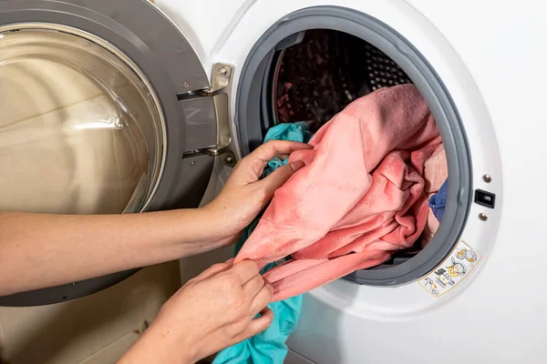 Çamaşır makinesinin yıkadığı renkli giysileri boşaltma işlemi.