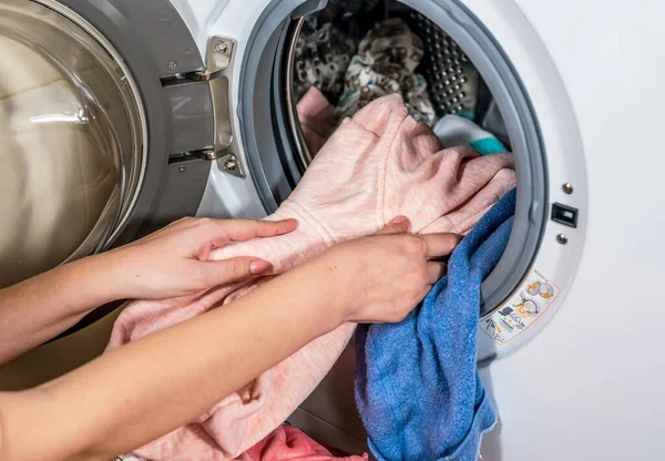 Çamaşır makinesinin yıkadığı renkli giysileri boşaltma işlemi.