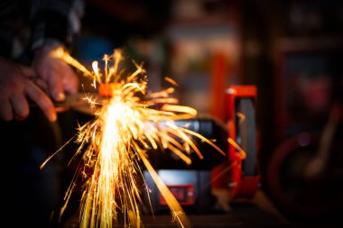 Metal üzerine makas keskinleştirme işlemi garajın arka planında çok sayıda parlak kıvılcımlar saçar.