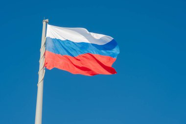 Rus bayrağı mavi gökyüzüne karşı rüzgarda dalgalanıyor.