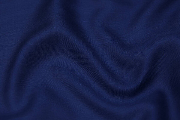Крупный план текстуры из натуральной голубой ткани или ткани того же цвета. Текстура ткани из натурального хлопка, шелка или шерсти, или льняного текстильного материала. Голубой холст.