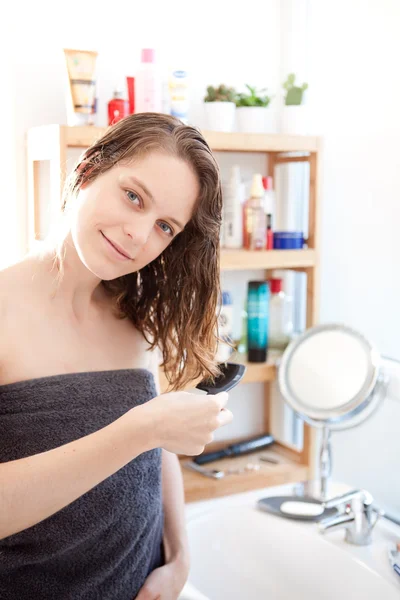 Jong meisje het verzorgen van haar haren in een badkamer — Stockfoto