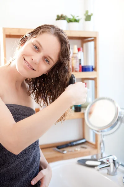 Jovem cuidando de seus cabelos em um banheiro — Fotografia de Stock