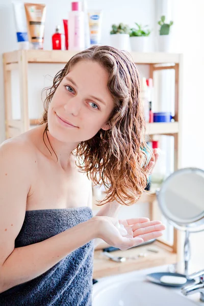 Молодая девушка ухаживает за волосами в ванной комнате — стоковое фото