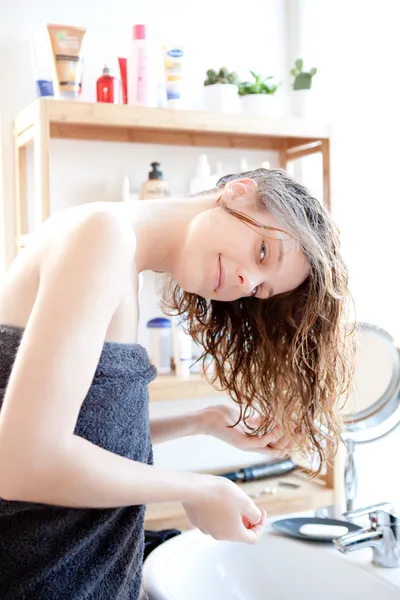 Jong meisje het verzorgen van haar haren in een badkamer — Stockfoto