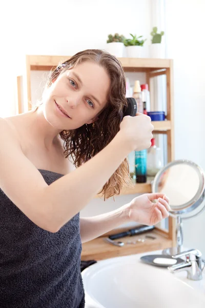 Молодая девушка ухаживает за волосами в ванной комнате — стоковое фото