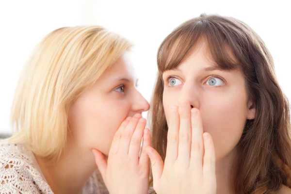 Blonde girl telling a secret to her best friend — Stock Photo, Image