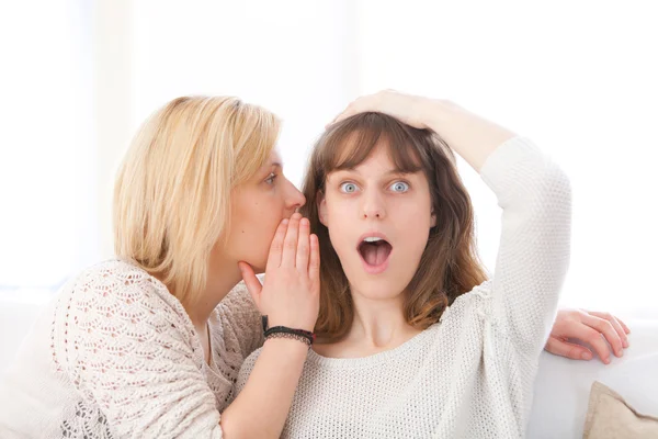 Blonde girl telling a secret to her best friend — Stock Photo, Image