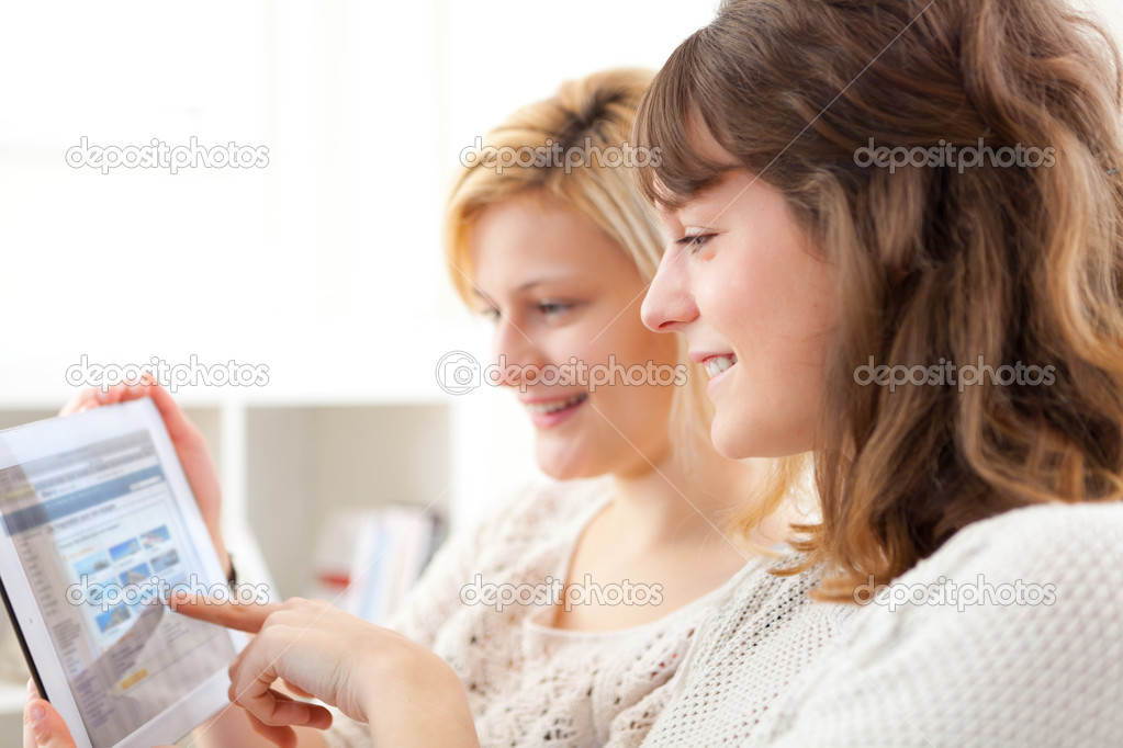 Girls choosing their holidays destination on tablet