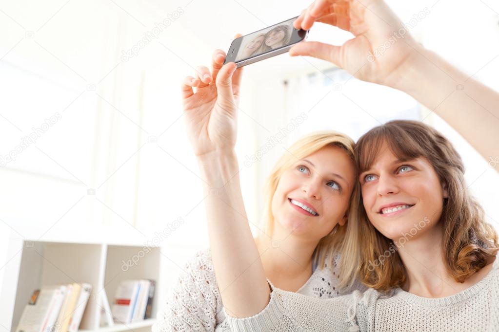 Girls on sofa taking selfie picture with smartphone