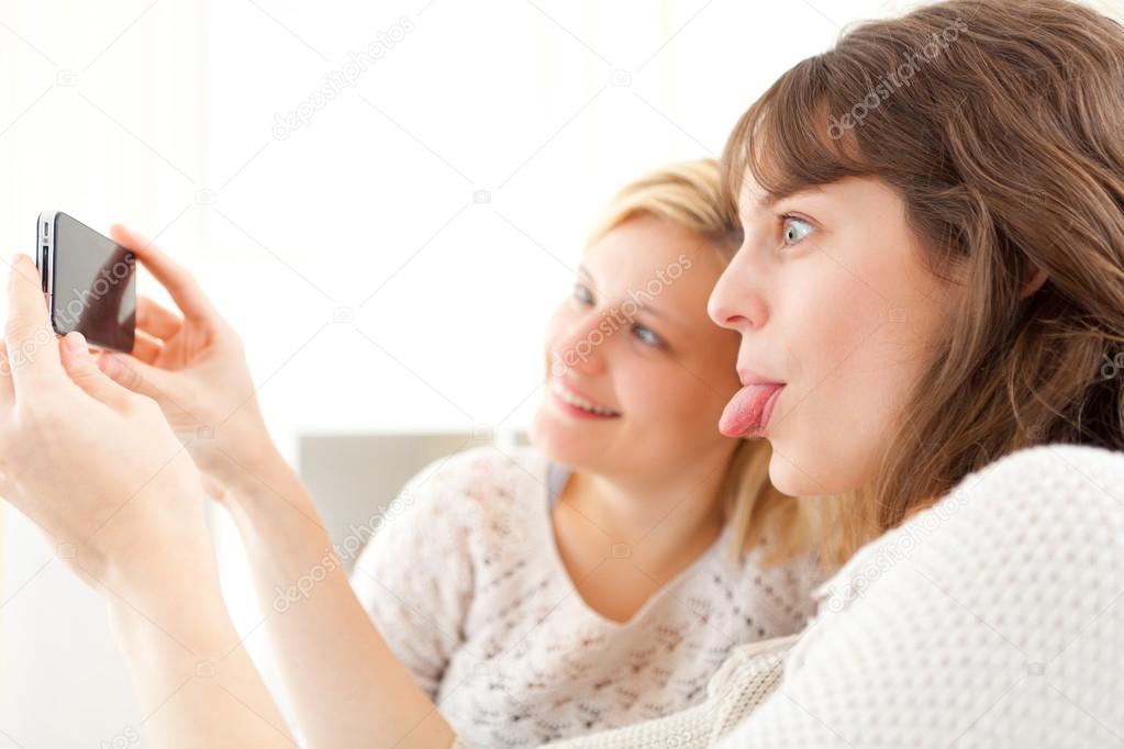 Girls on sofa taking selfie picture with smartphone