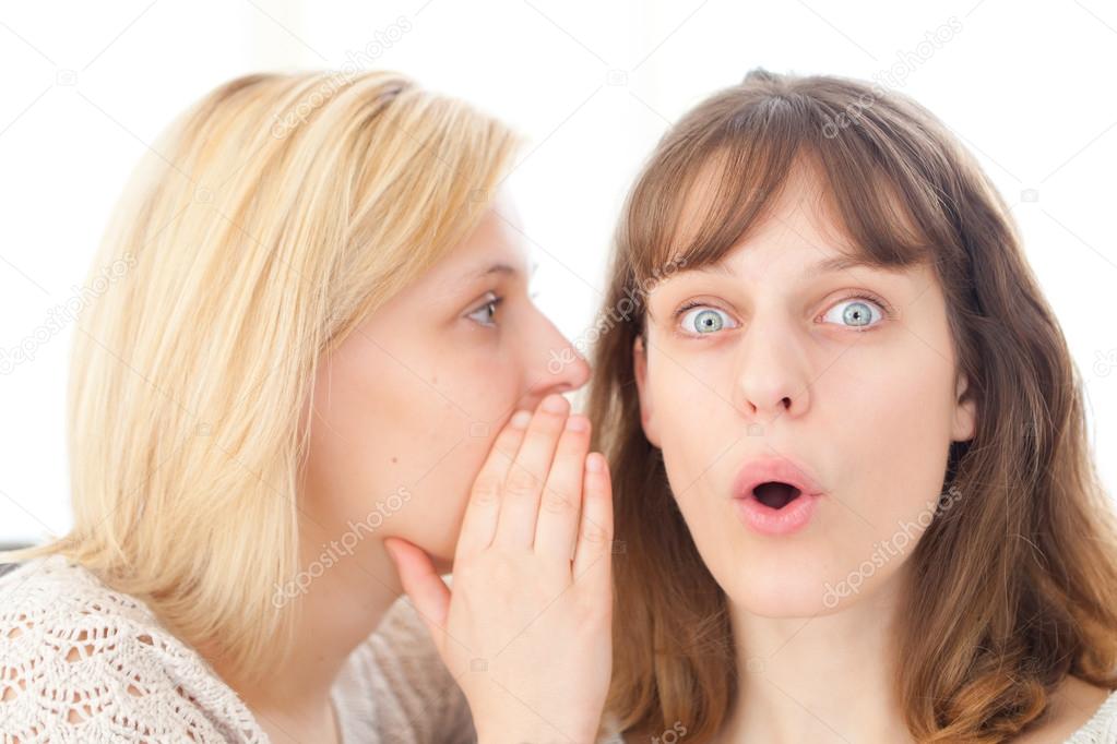 Blonde girl telling a secret to her best friend