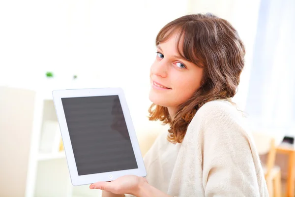 Portret van jonge lachende vrouw met behulp van een Tablet PC op een sofa — Stockfoto