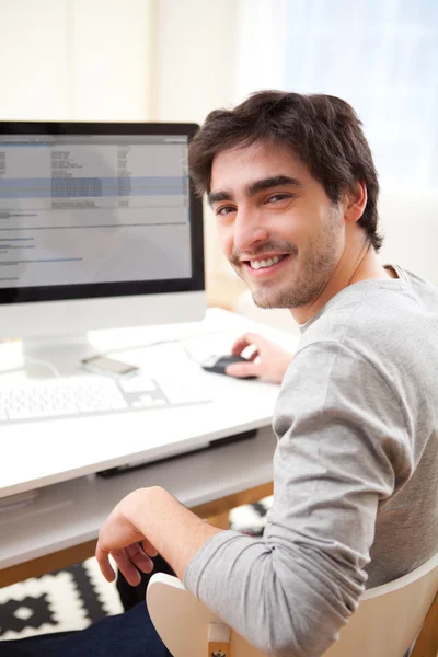 Joven hombre sonriente delante de la computadora — Foto de Stock