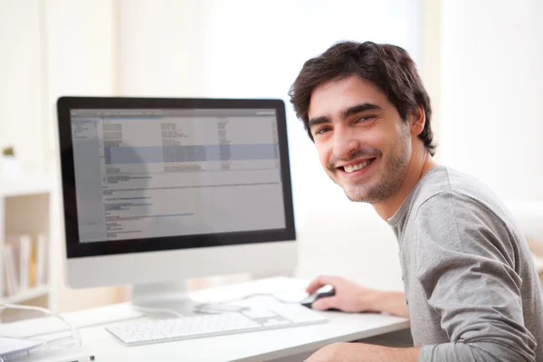 Joven hombre sonriente delante de la computadora — Foto de Stock