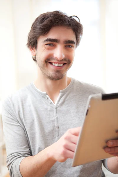 Jeune homme souriant utilisant une tablette — Photo