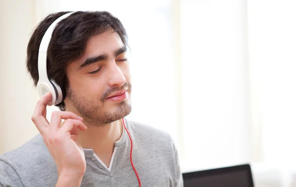 Joven hombre relajado escuchando música en la oficina —  Fotos de Stock
