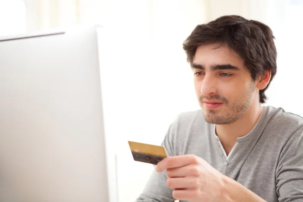 Joven hombre relajado que paga en línea con tarjeta de crédito — Foto de Stock