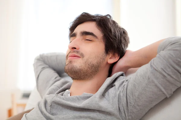 Junger Mann entspannt sich während einer Pause auf dem Sofa — Stockfoto