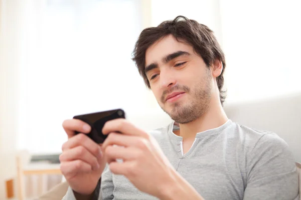 Entspannter junger Mann schreibt Text auf dem Sofa — Stockfoto