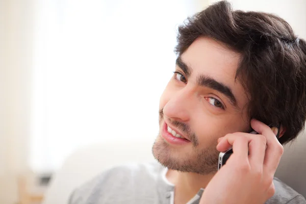 Young attractive man having a call in a sofa — Stock Photo, Image