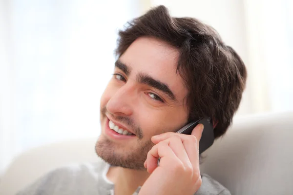 Young attractive man having a call in a sofa — Stock Photo, Image