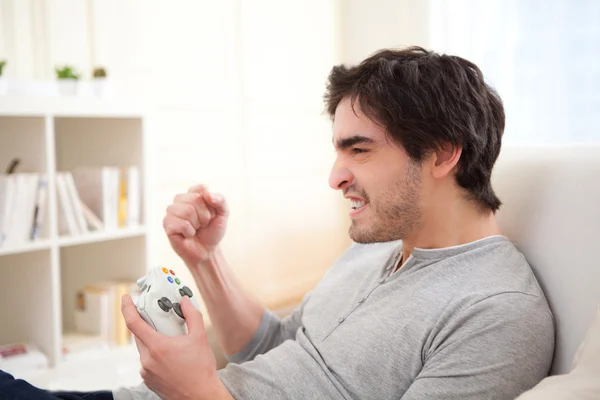 Aantrekkelijke jonge man spelen videospelletjes online in een bank — Stockfoto