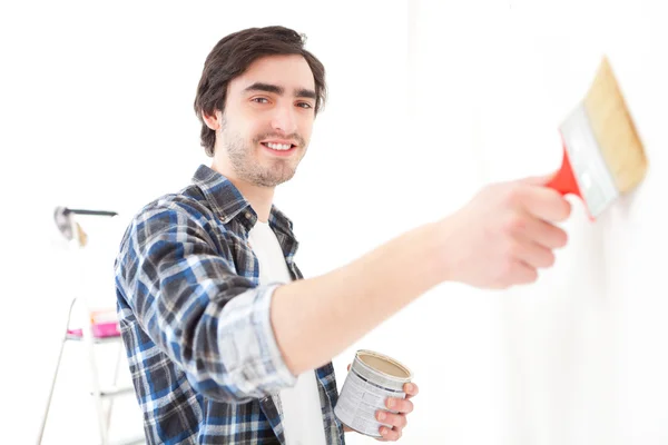 Jovem atraente pintando uma parede em seu novo apartamento — Fotografia de Stock