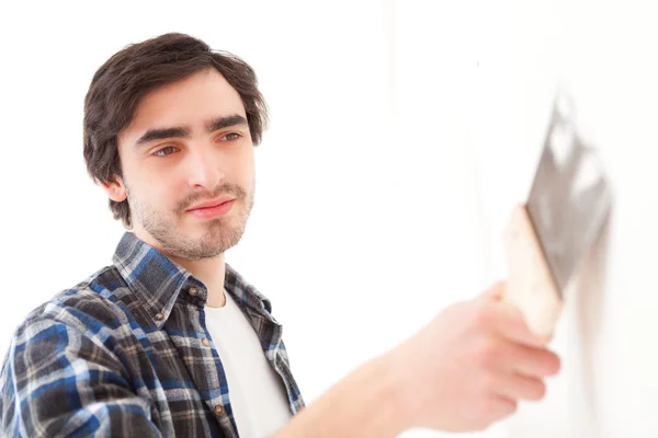 Attraktiver junger Mann schrubbt eine Wand in seiner Wohnung — Stockfoto