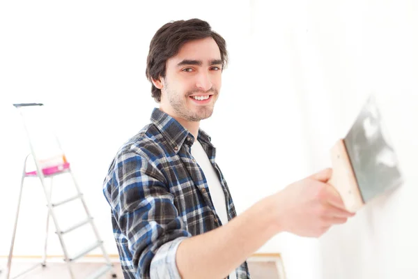 Привлекательный молодой человек чистит стену в своей квартире — стоковое фото