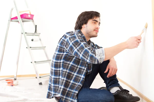 Jovem atraente pintando uma parede em seu novo apartamento — Fotografia de Stock