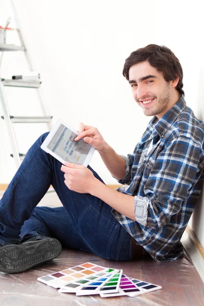 Hombre joven usando la tableta al elegir el color de su piso —  Fotos de Stock